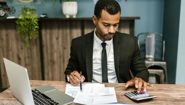 Business owner at a desk comparing quotes with a laptop and a calculator