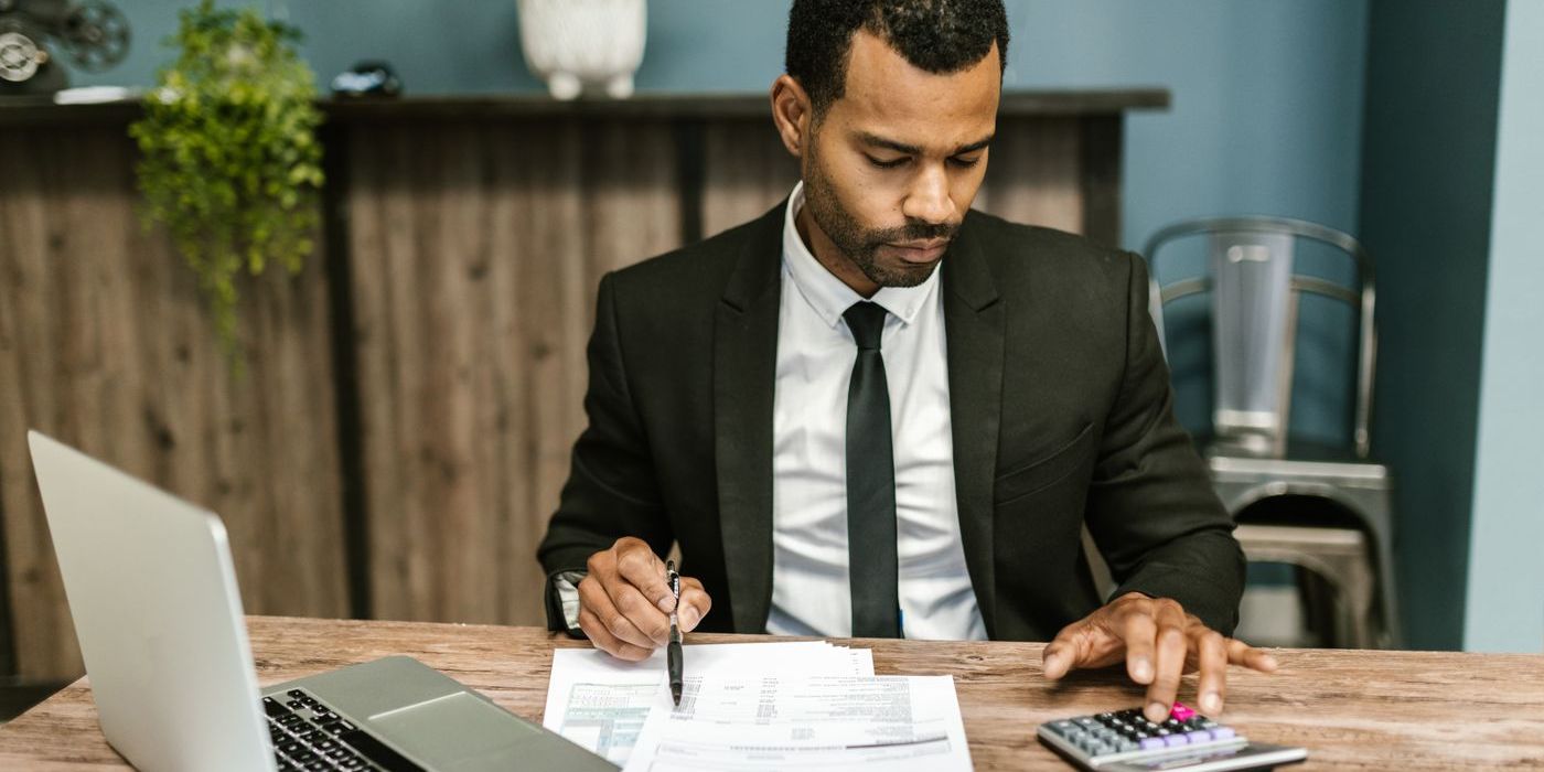 Dirigeant à son bureau comparant des devis avec un ordinateur portable et une calculatrice
