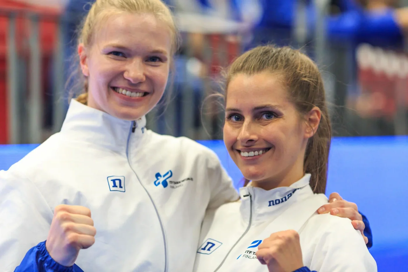 Kaksi hymyilevää Taekwon-Do-harrastajaa verryttelyasuissa