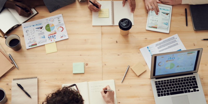 People meeting around a table with post-it notes, coffee, and charts
