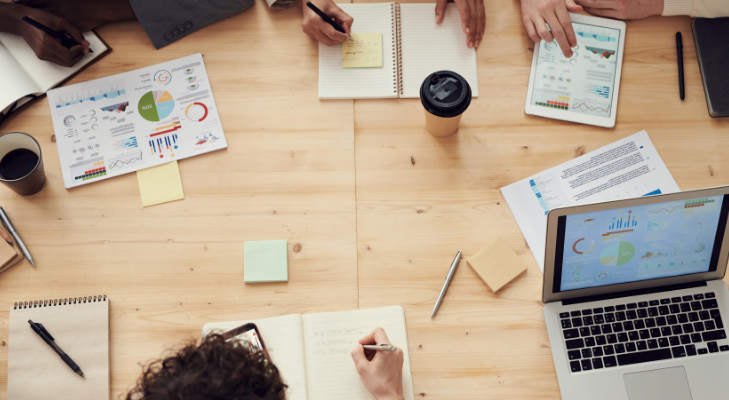 People meeting around a table with post-it notes, coffee, and charts