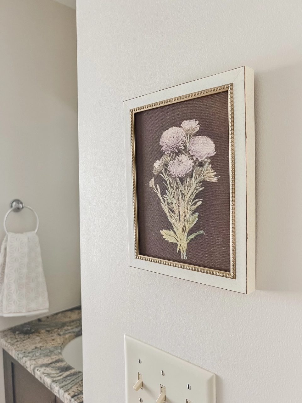 Framed floral print on the bathroom wall beside the vanity