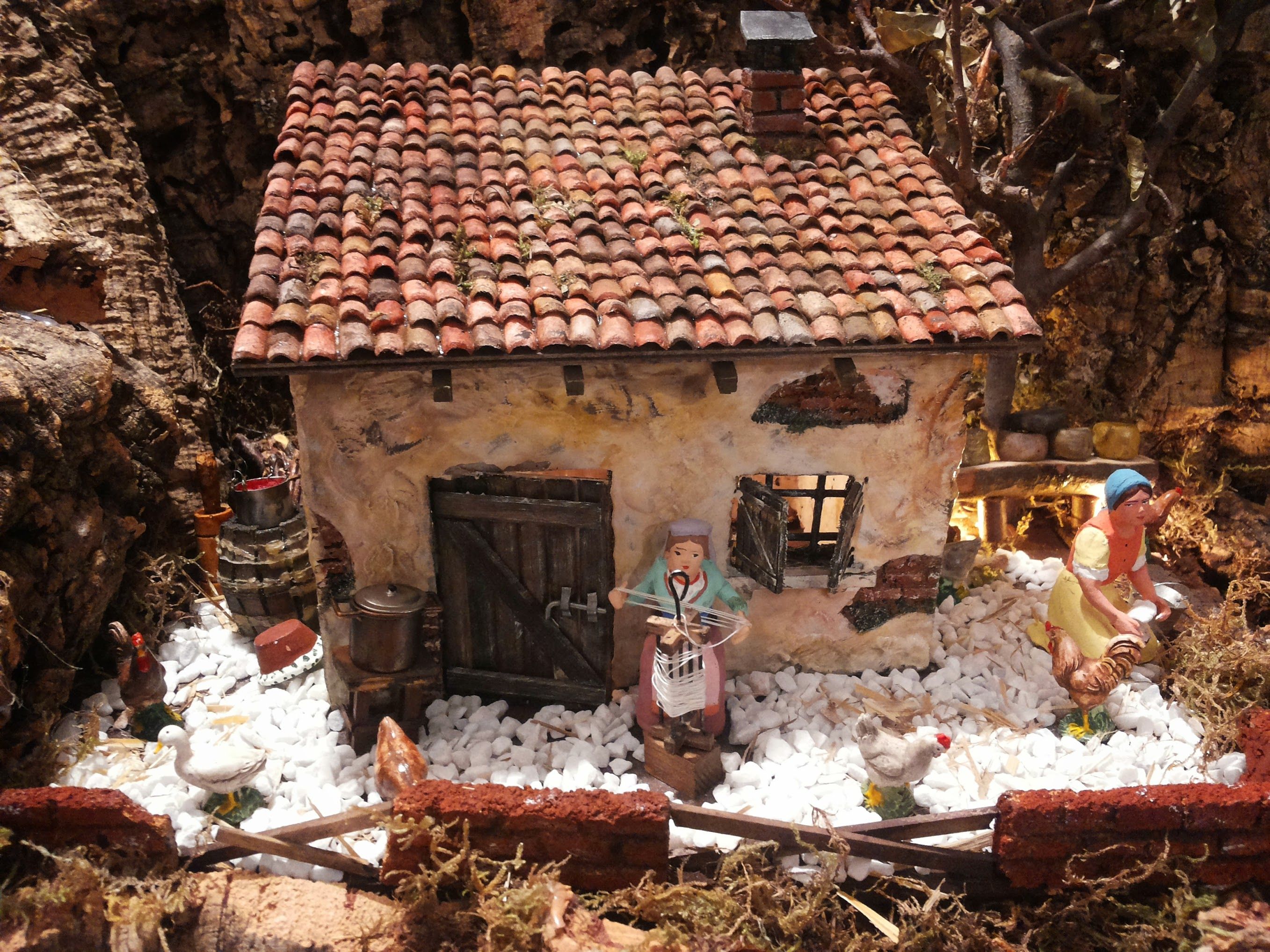Casetta con cortile in pietrisco bianco, galline, oche e una figura al filatoio
