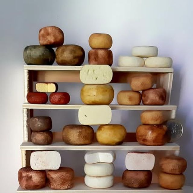 Scaffale a quattro ripiani con forme di formaggio di diverse dimensioni