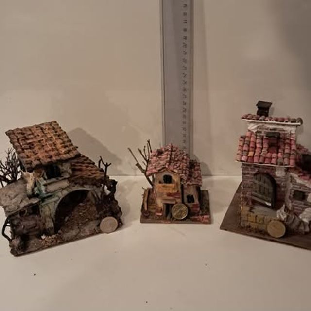 Tre casette rustiche in miniatura di stile diverso, fotografate insieme con un righello