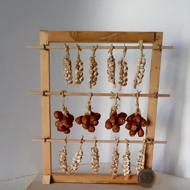 Rastrelliera in legno naturale con trecce d'aglio, grappoli di pomodorini e cipolle