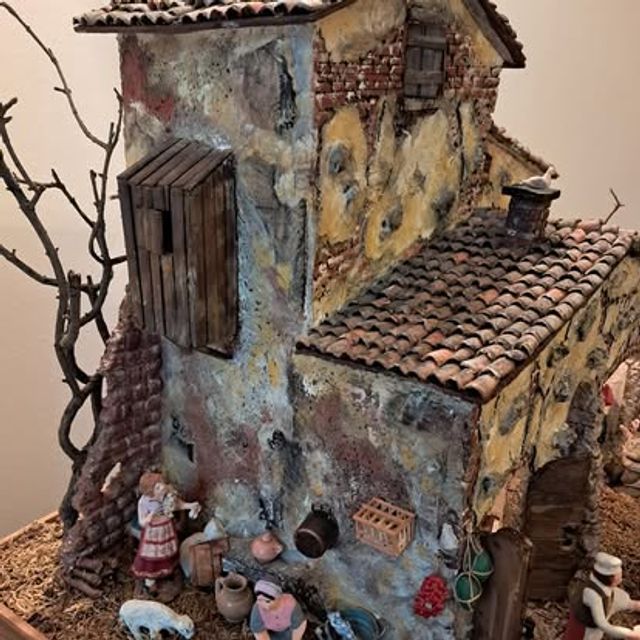 Grande scenografia con casale, ruota di mulino, banchetto del mercato e numerose figure