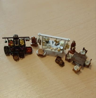 Piccolo set di accessori da mercato: carretto di frutta, rastrelliera di formaggi e tavolino con sedie