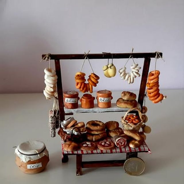 Bancarella con pane, taralli e salumi appesi, vasetti d'olio a fianco
