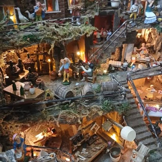 Veduta dall'alto di un grande presepe con cantina, bottega e scalinate illuminate