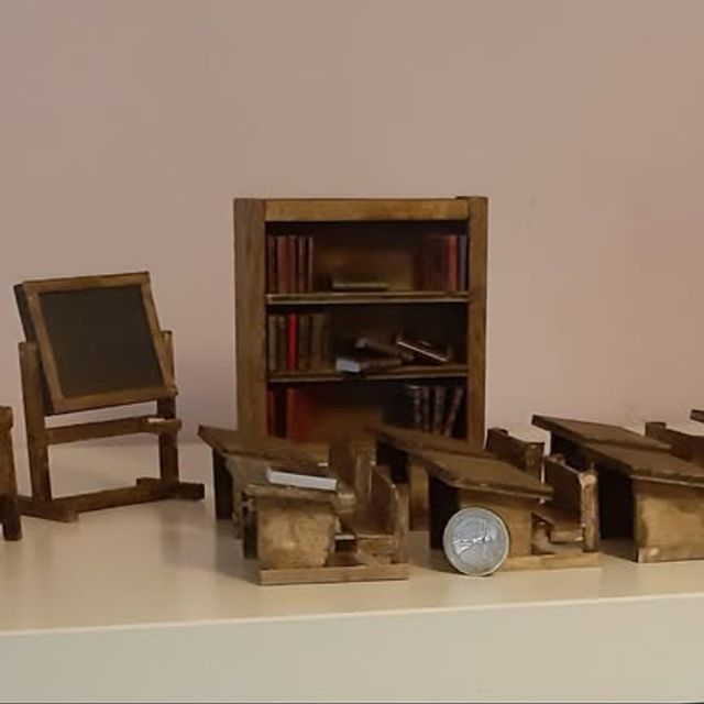 Piccola aula scolastica con banchi, lavagna e libreria in legno