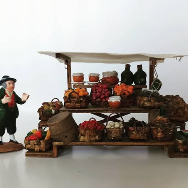 Bancarella di frutta e verdura con tendina bianca, bottiglie e cesti colmi