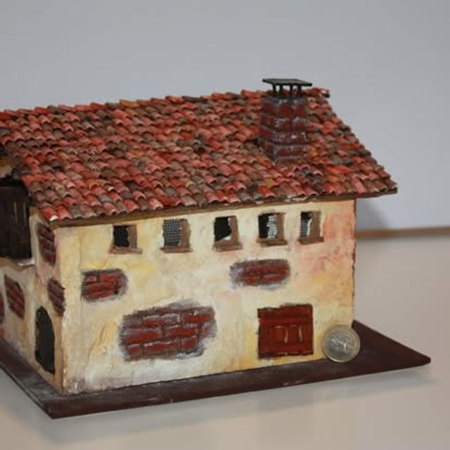 Dettaglio di casetta con muratura a vista, mattoncini decorativi e finestre a grata