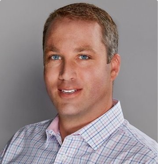 Man in a checkered shirt sitting in front of a grey background