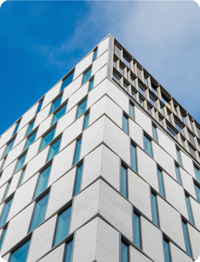 The corner of a tall glass and metal building against a blue sky