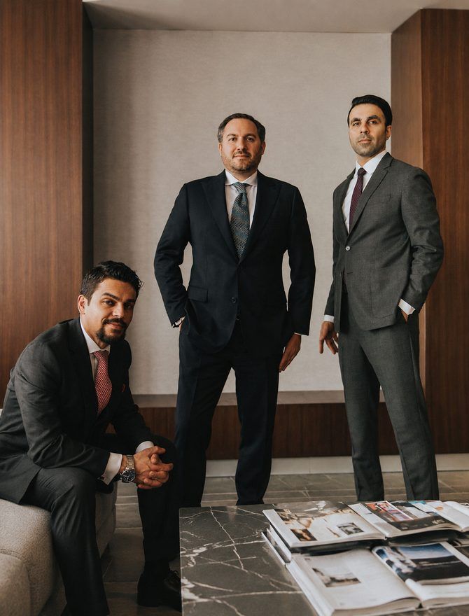 Three lawyers in suits photographed in a wood-panelled boardroom