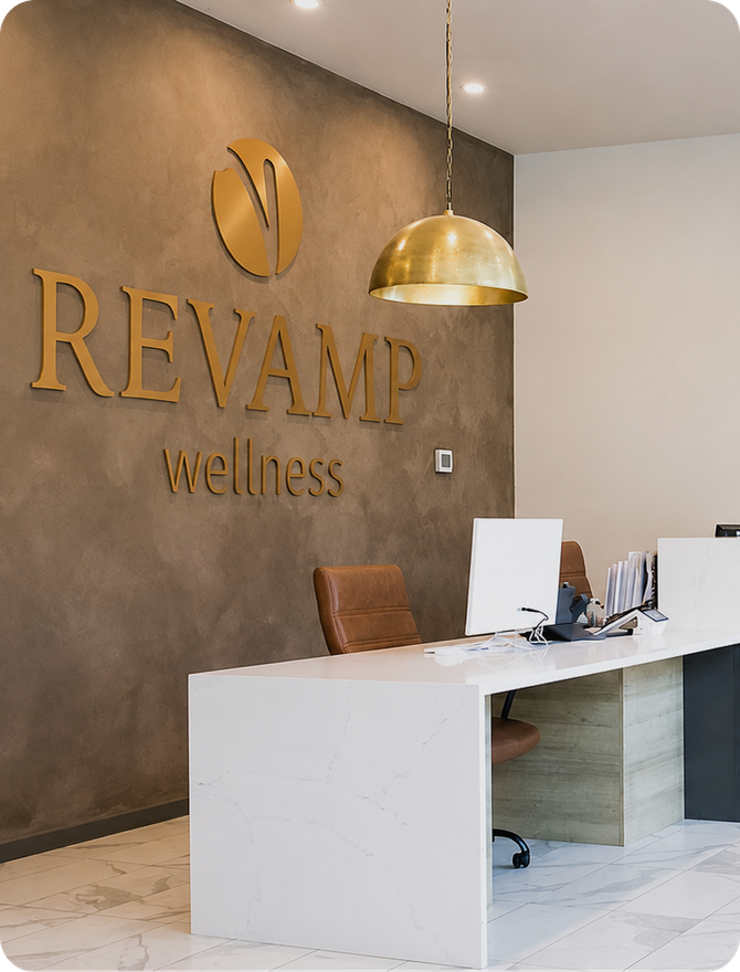 The Revamp Wellness reception desk under a brass pendant light
