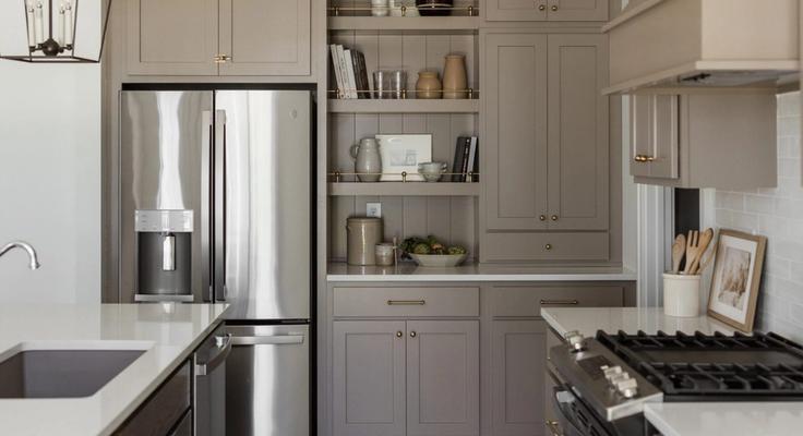 A finished kitchen with a stainless steel refrigerator and pale cabinetry