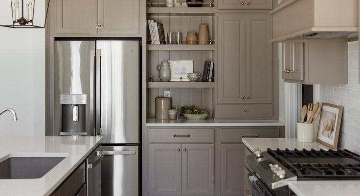 A finished kitchen with a stainless steel refrigerator and pale cabinetry