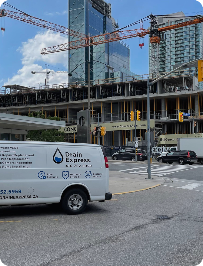 A Drain Express service van parked on a city street beside a high-rise construction site