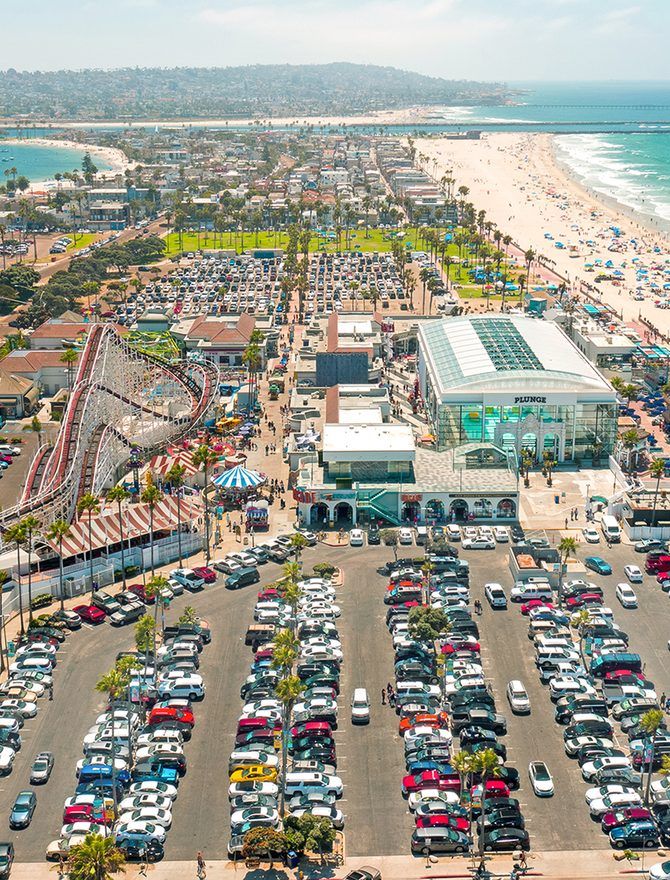 An aerial view of a beachfront district with a boardwalk and car parks