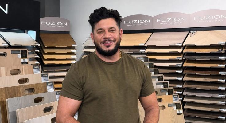 Santino Bernardo of GreenValley Flooring in the showroom, in front of racks of flooring samples