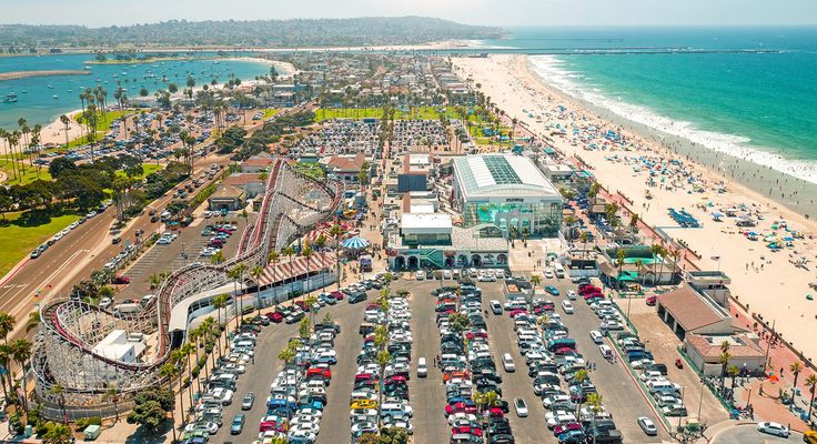 An aerial view of a beachfront district with a boardwalk and car parks
