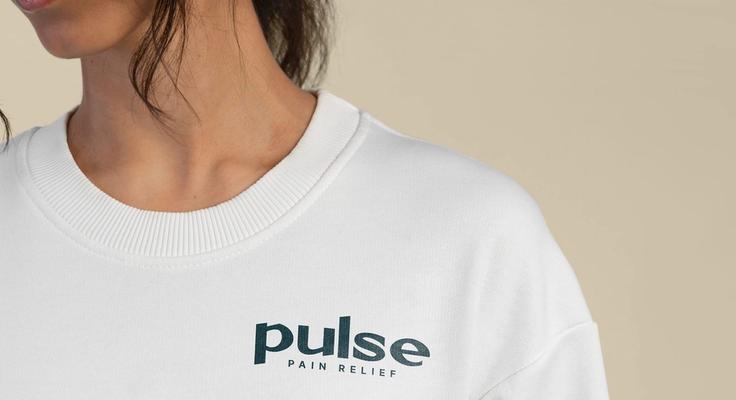A close-up of a cream sweatshirt printed with the Pulse Pain Relief logo