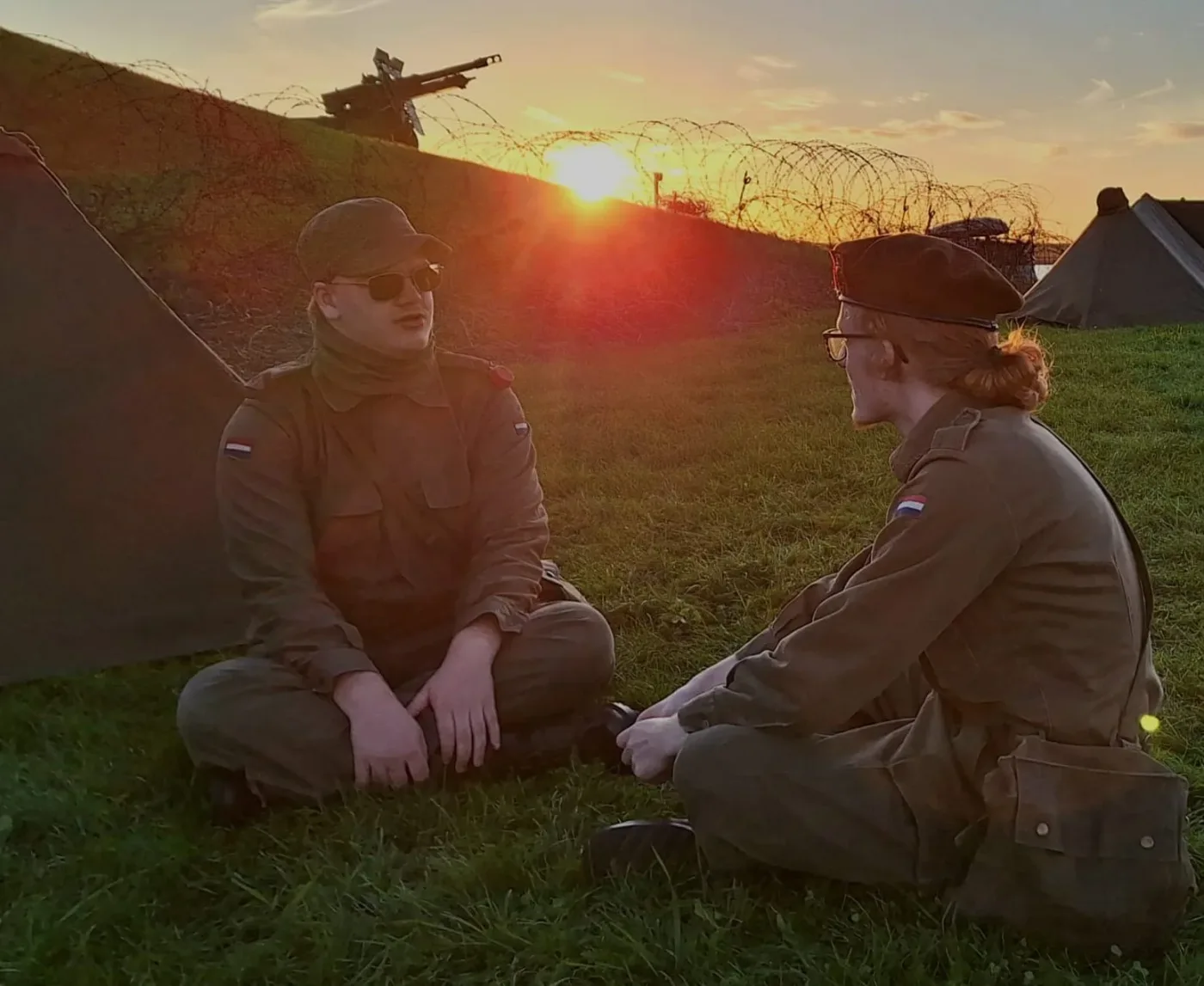Twee groepsleden bij hun kamp in het avondlicht