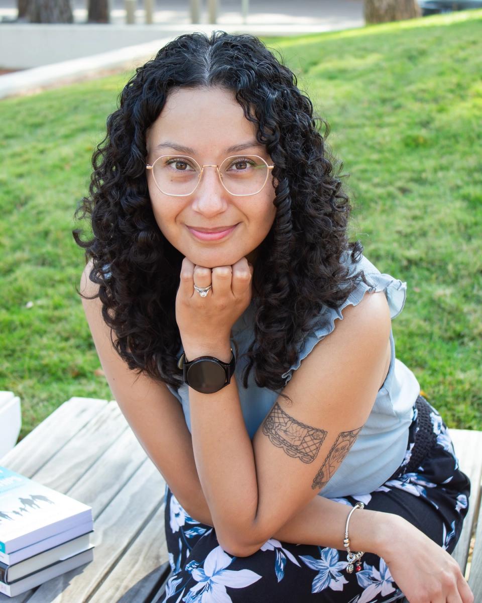 Priscilla Dominguez smiling outdoors, resting her chin on her hand