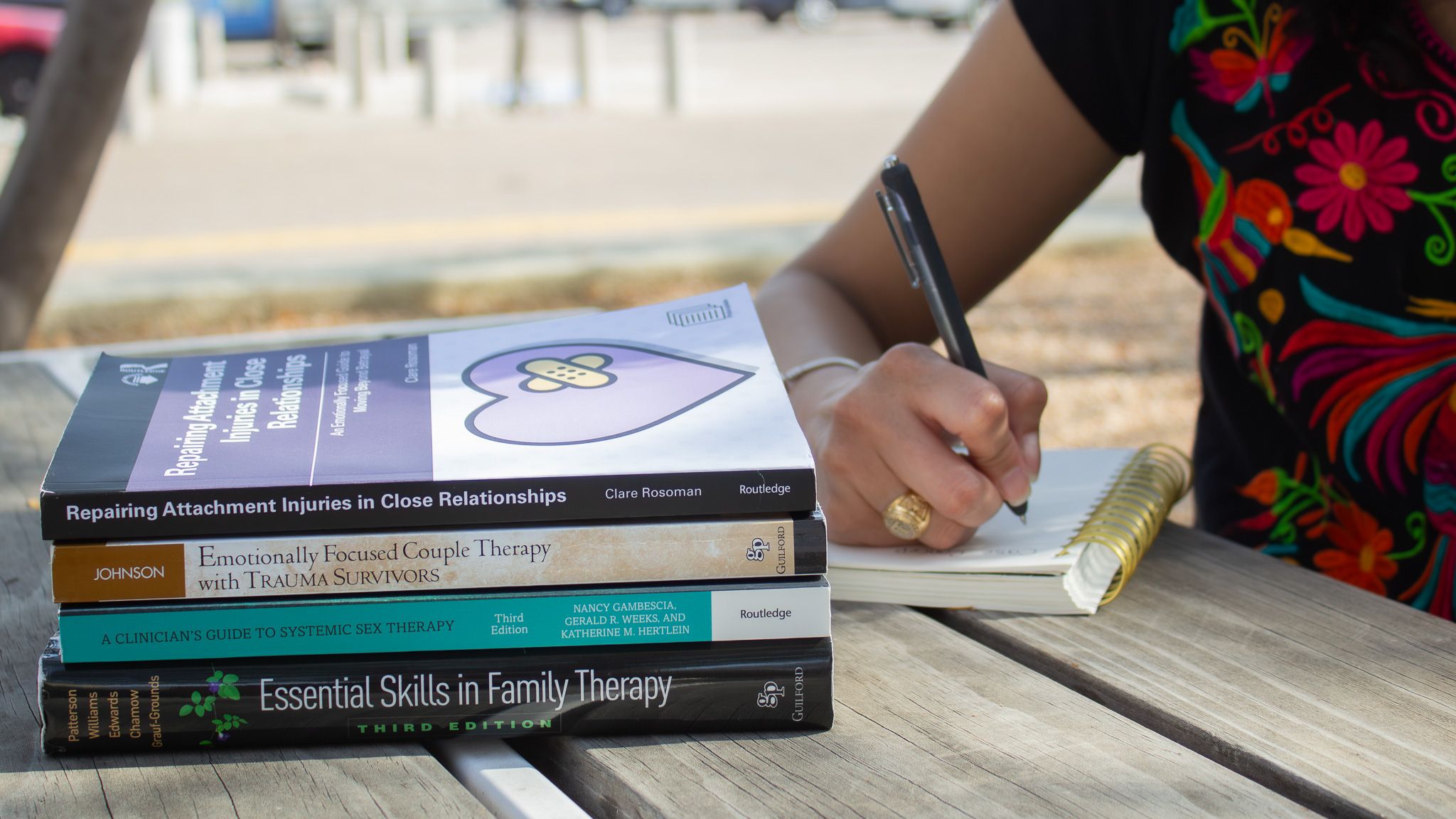 A stack of family therapy and Emotionally Focused Therapy books beside a notebook