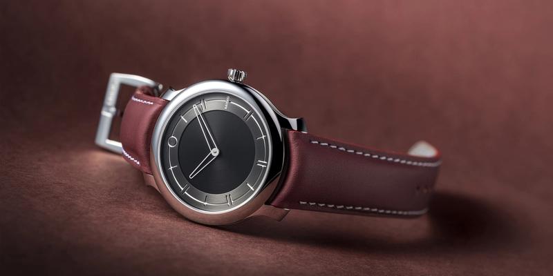 Ming 27.01 watch on brown leather strap laying on side on table.
