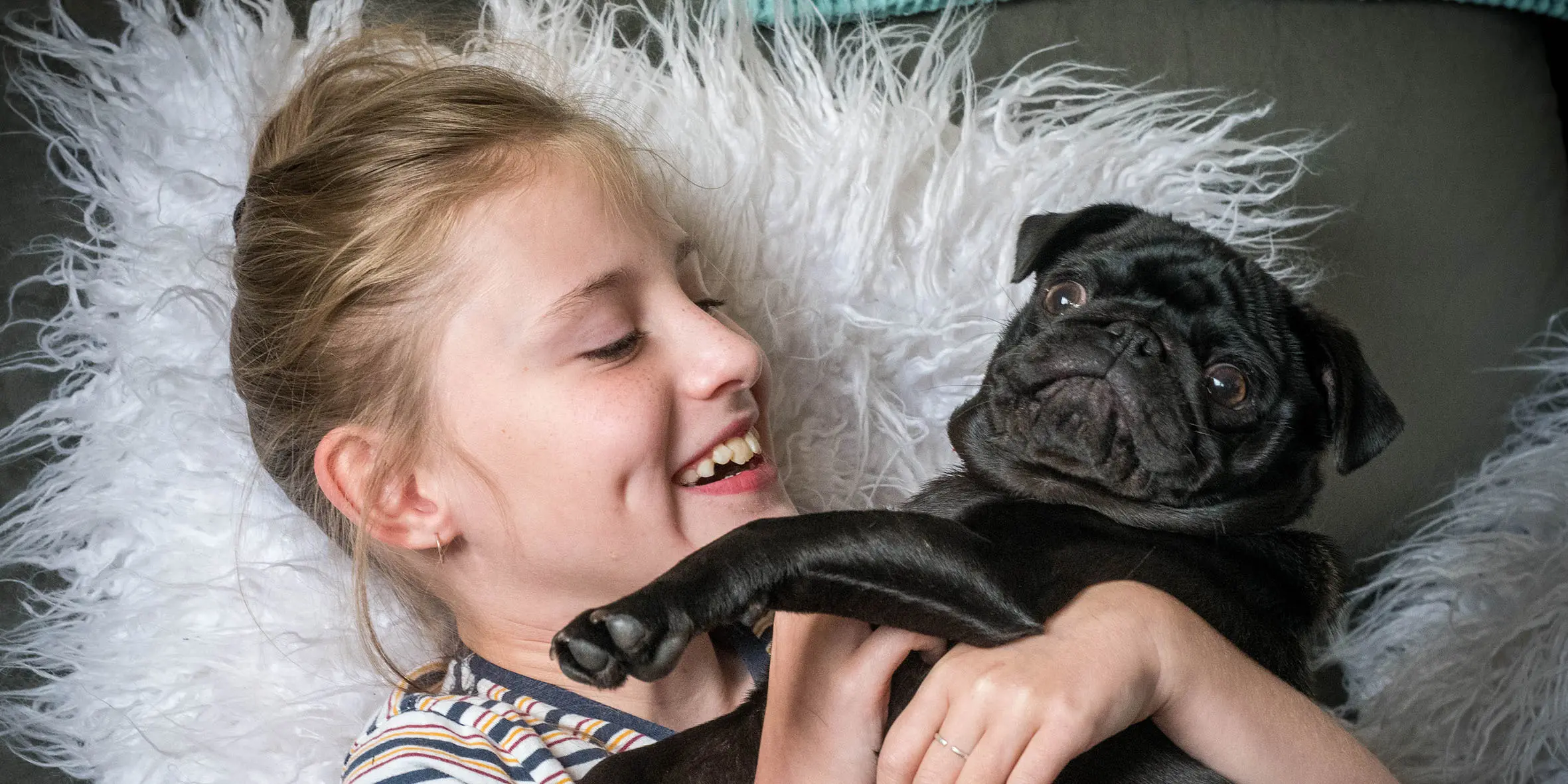 Kids Charity wish kid Grace holding her black pug puppy