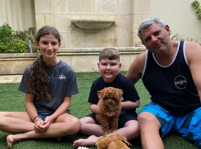 Make-A-Wish Australia wish kid Carmelo sat with his family and new cavoodle