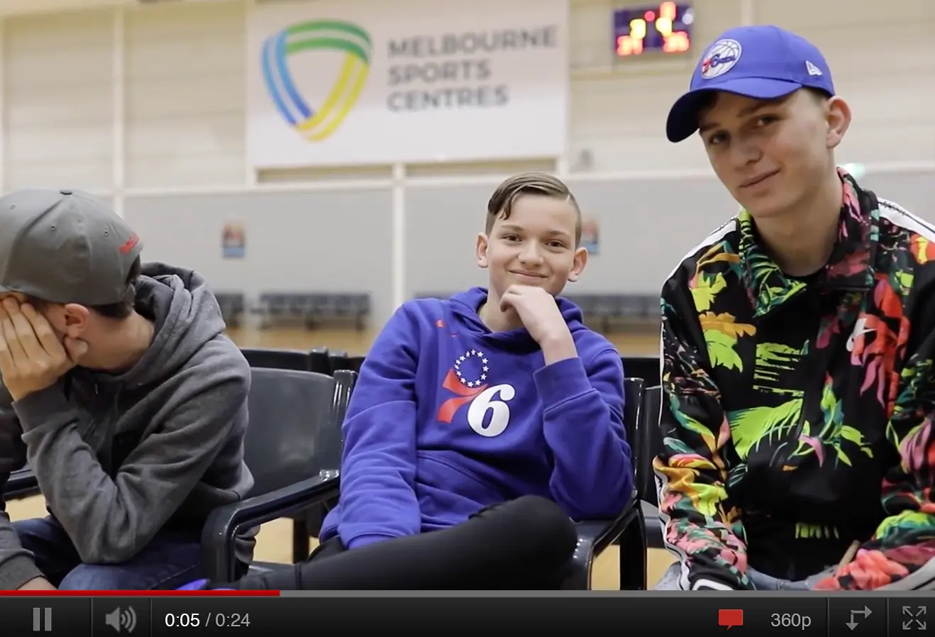 Make-A-Wish Australia wish kid Claude sat at the basketball court with friends