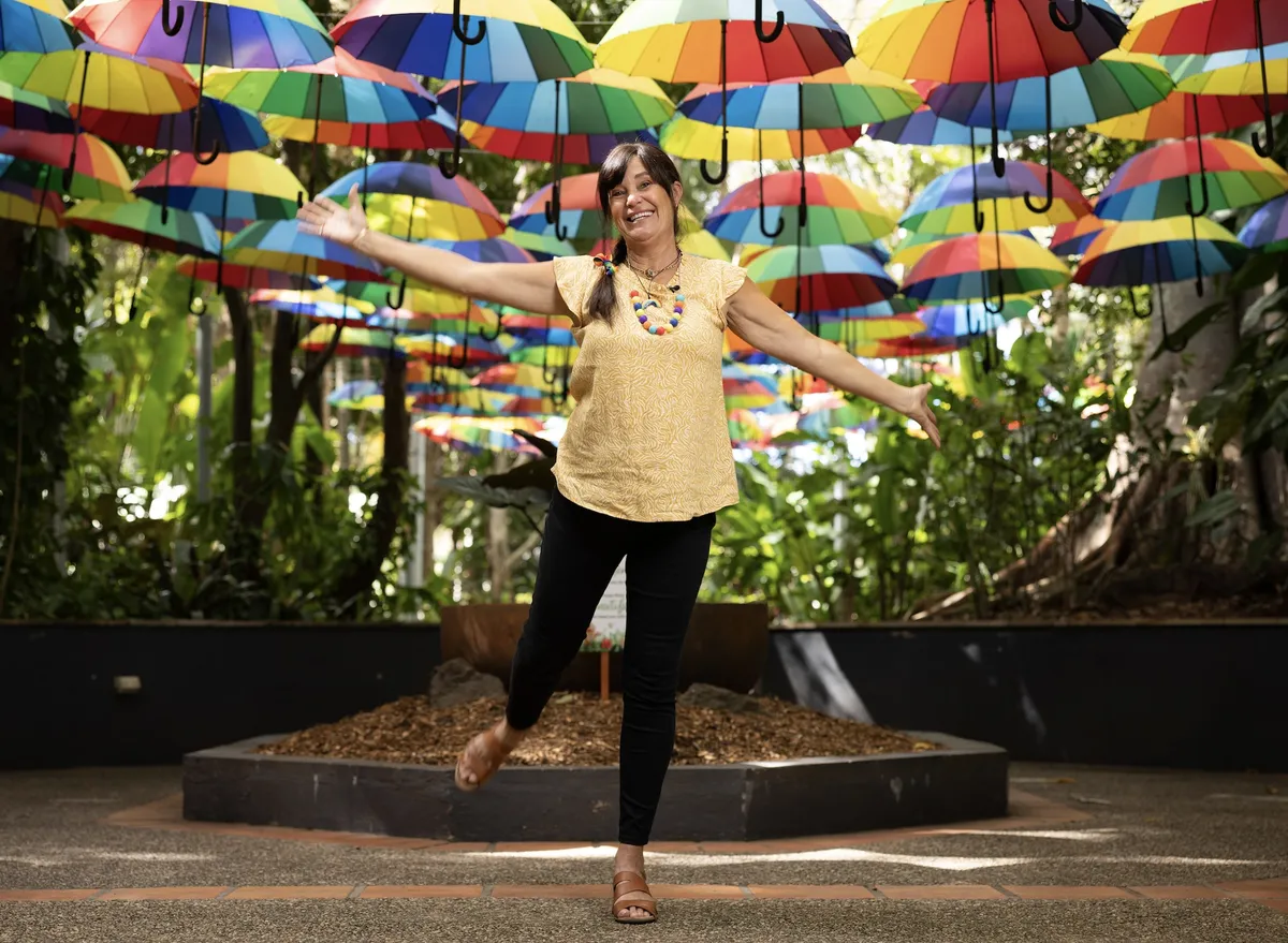 Happy artist stands in front of rainbow umbrellas