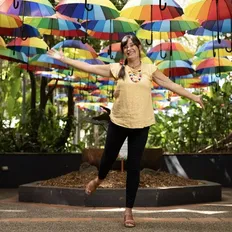 Happy artist stands in front of rainbow umbrellas