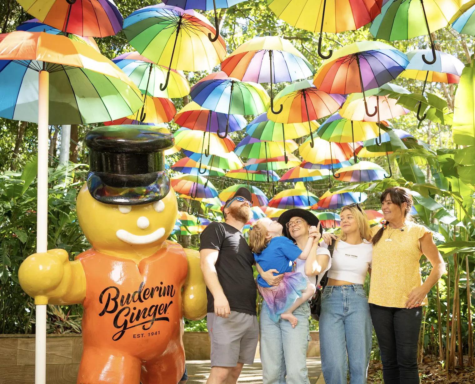 Happy wish child and family stand with rainbow umbrellas