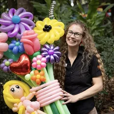 Smiling woman holds colourful inflatable flowers