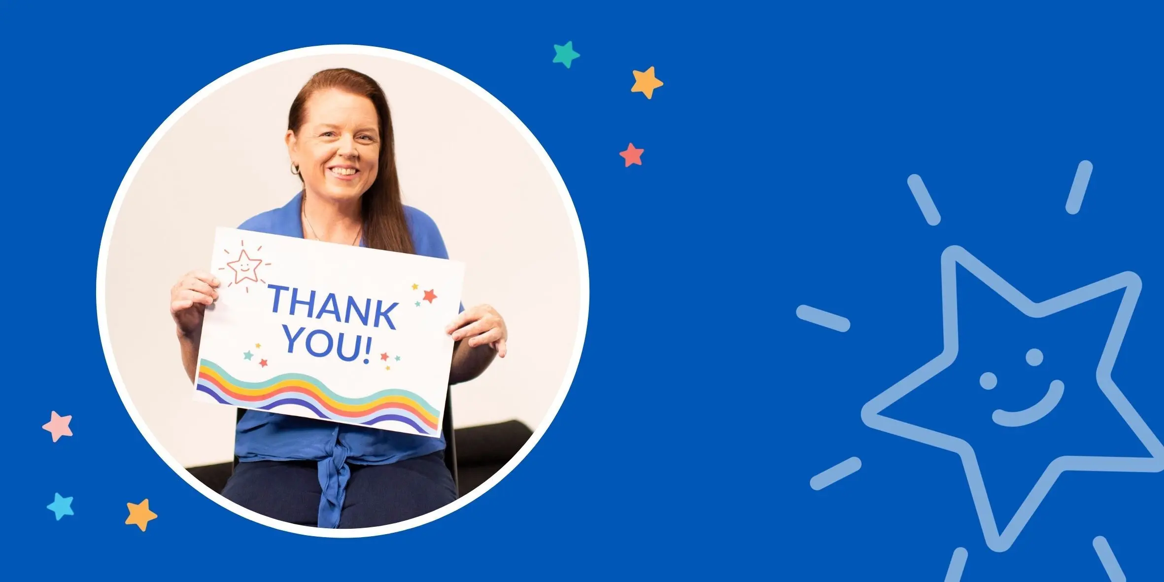 Louise sitting down, smiling and holding a card that says thank you