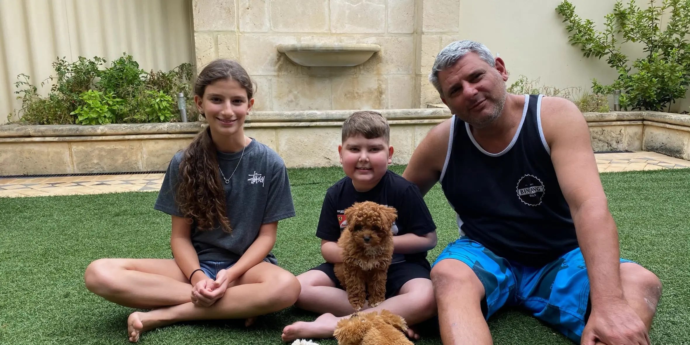 Make-A-Wish Australia wish kid Carmelo sat with his family and new cavoodle