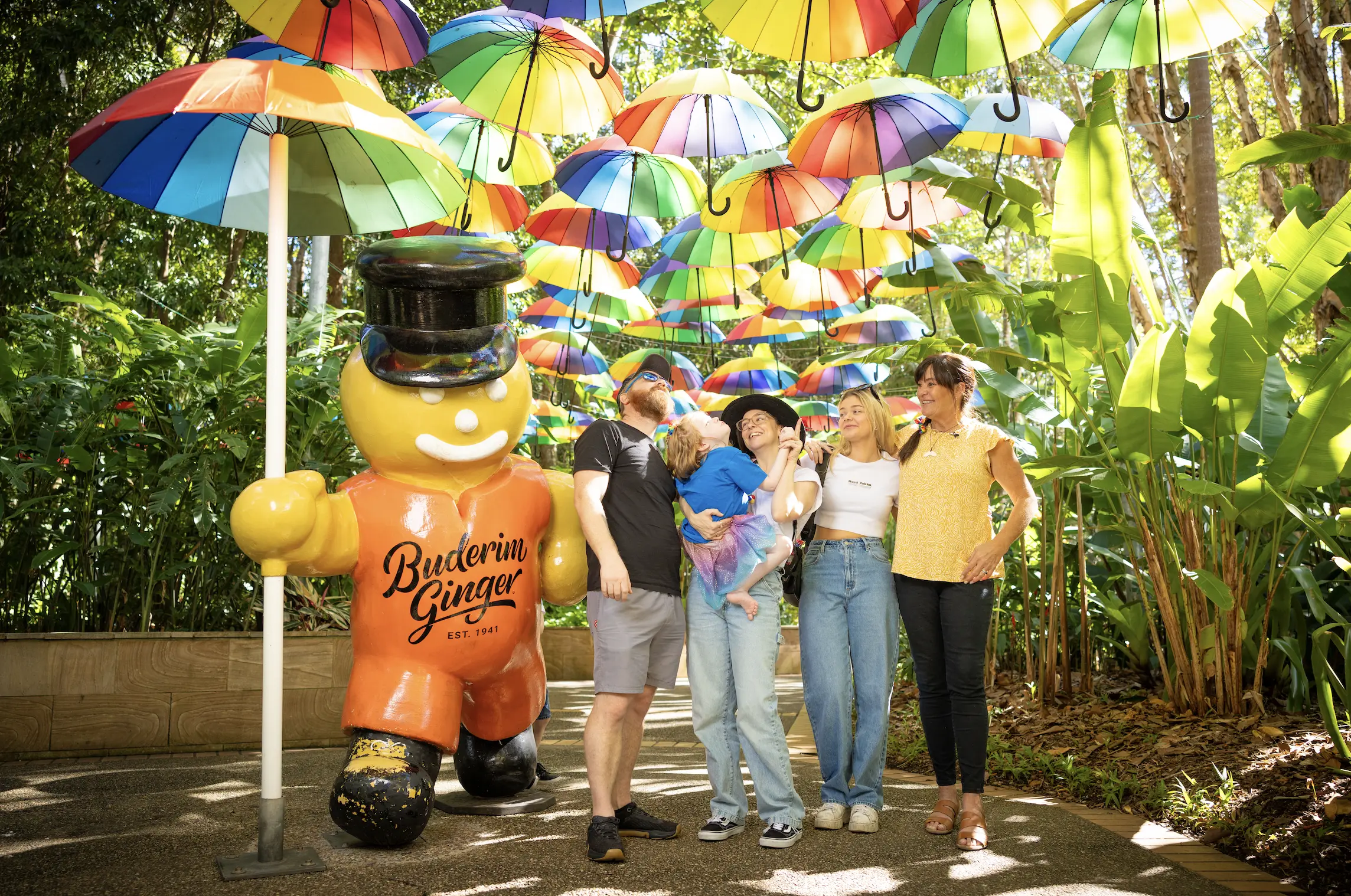 Happy wish child and family stand with rainbow umbrellas