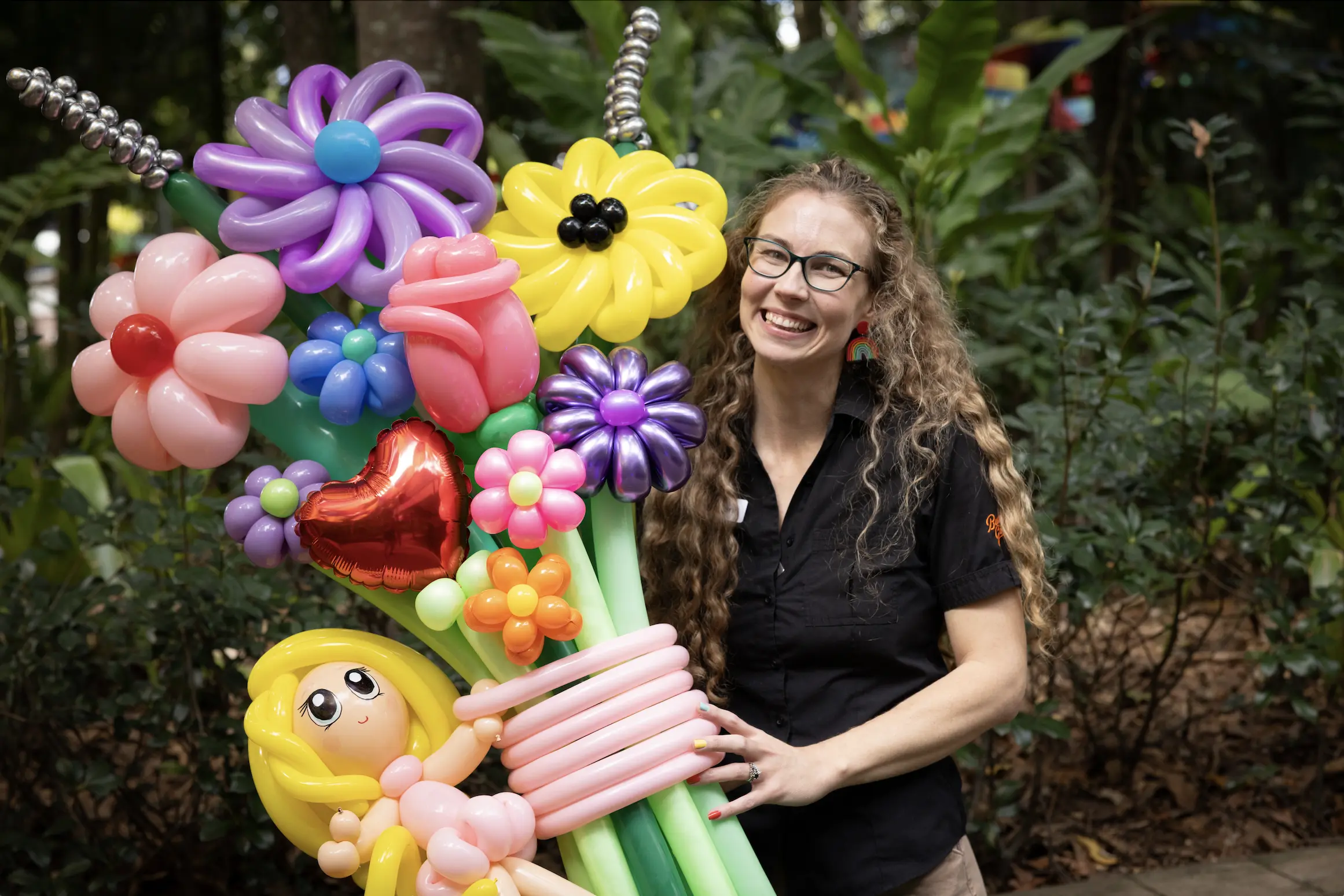 Smiling woman holds colourful inflatable flowers