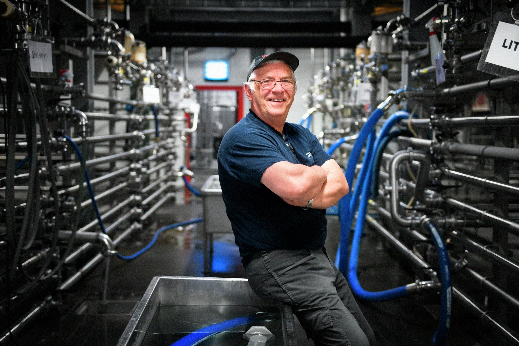 Arbeider står foran rør i krom i fabrikk