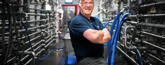 Arbeider står foran rør i krom i fabrikk