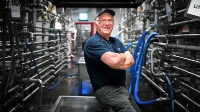 Arbeider står foran rør i krom i fabrikk