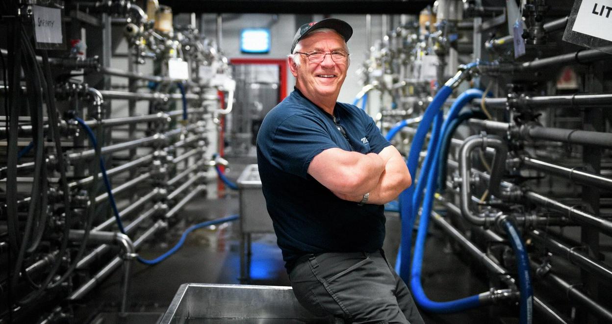 Arbeider står foran rør i krom i fabrikk