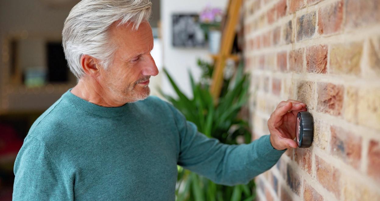 En energirådgiver måler temperaturen i rommet