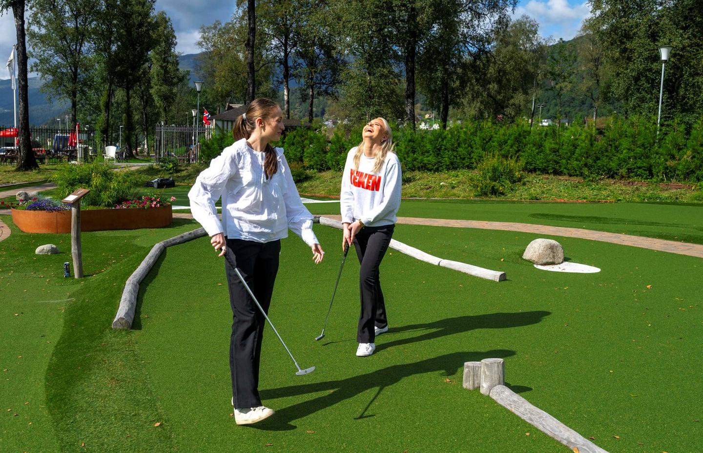 Julie Vikeså Solbakken (t.v) og Siri Tveitane slår et slag for Sauda. Et lite et på minigolfbanen, kloss ved smelteverket.
