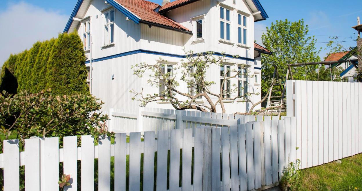 En godt vedlikeholdt hvit villa med frodig grønn hage